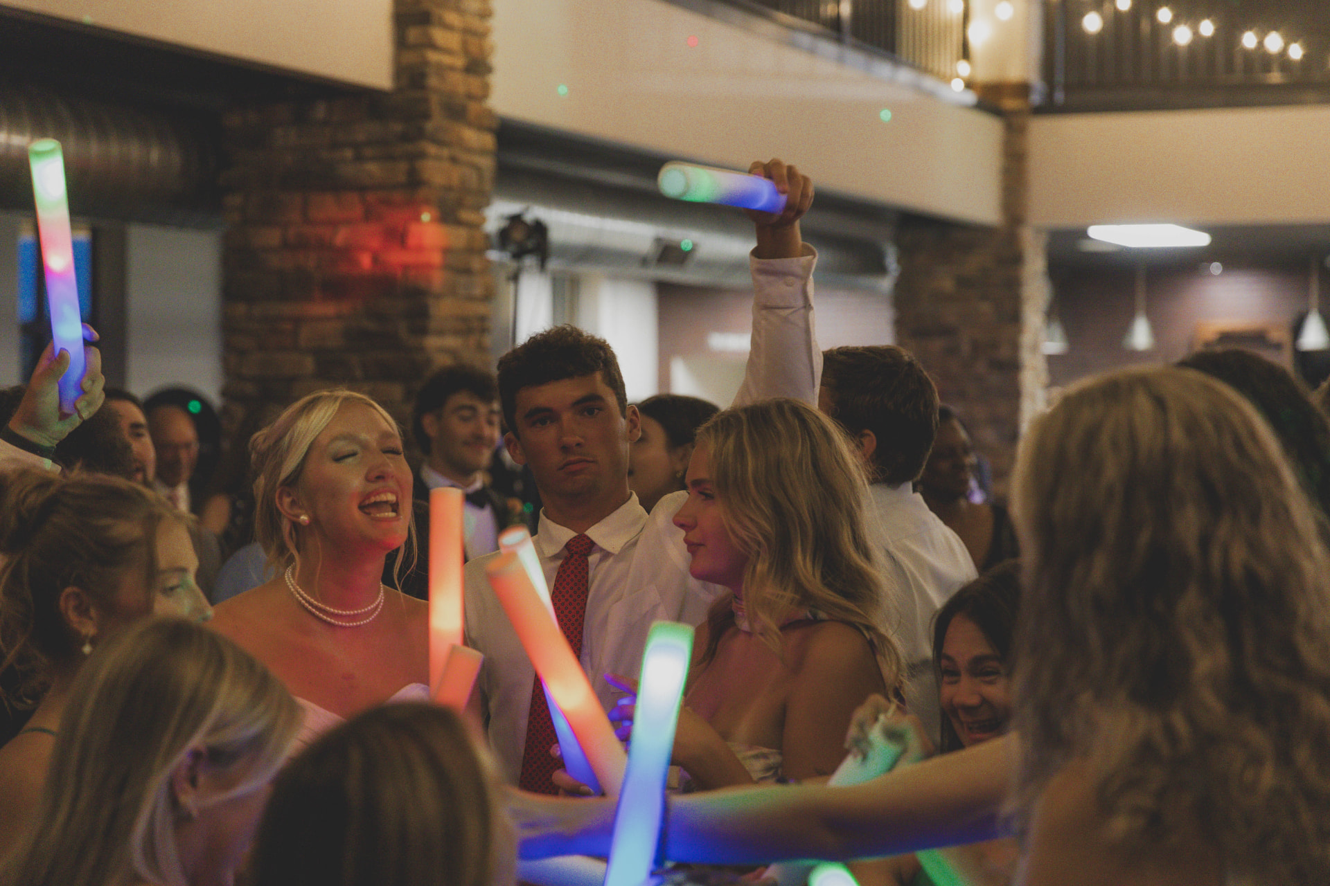 Bride singing on the dance floor surrounded by friends with glow sticks at a Missouri wedding reception