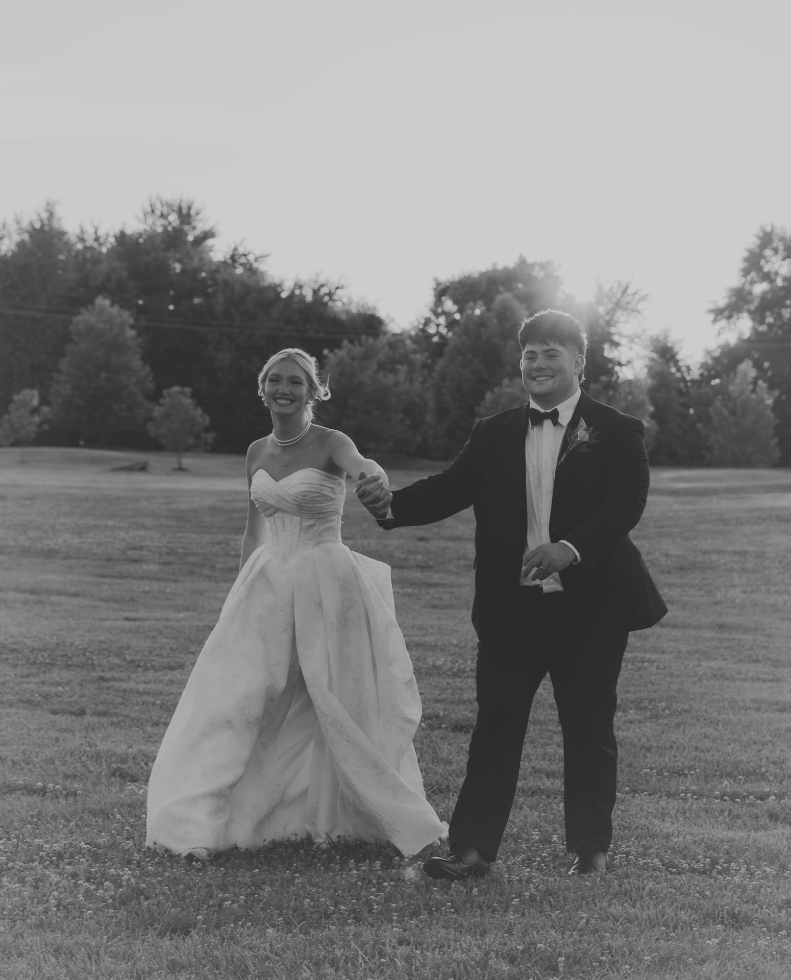 Black and white portrait of newlyweds laughing as they walk at sunset in Columbia, Missouri