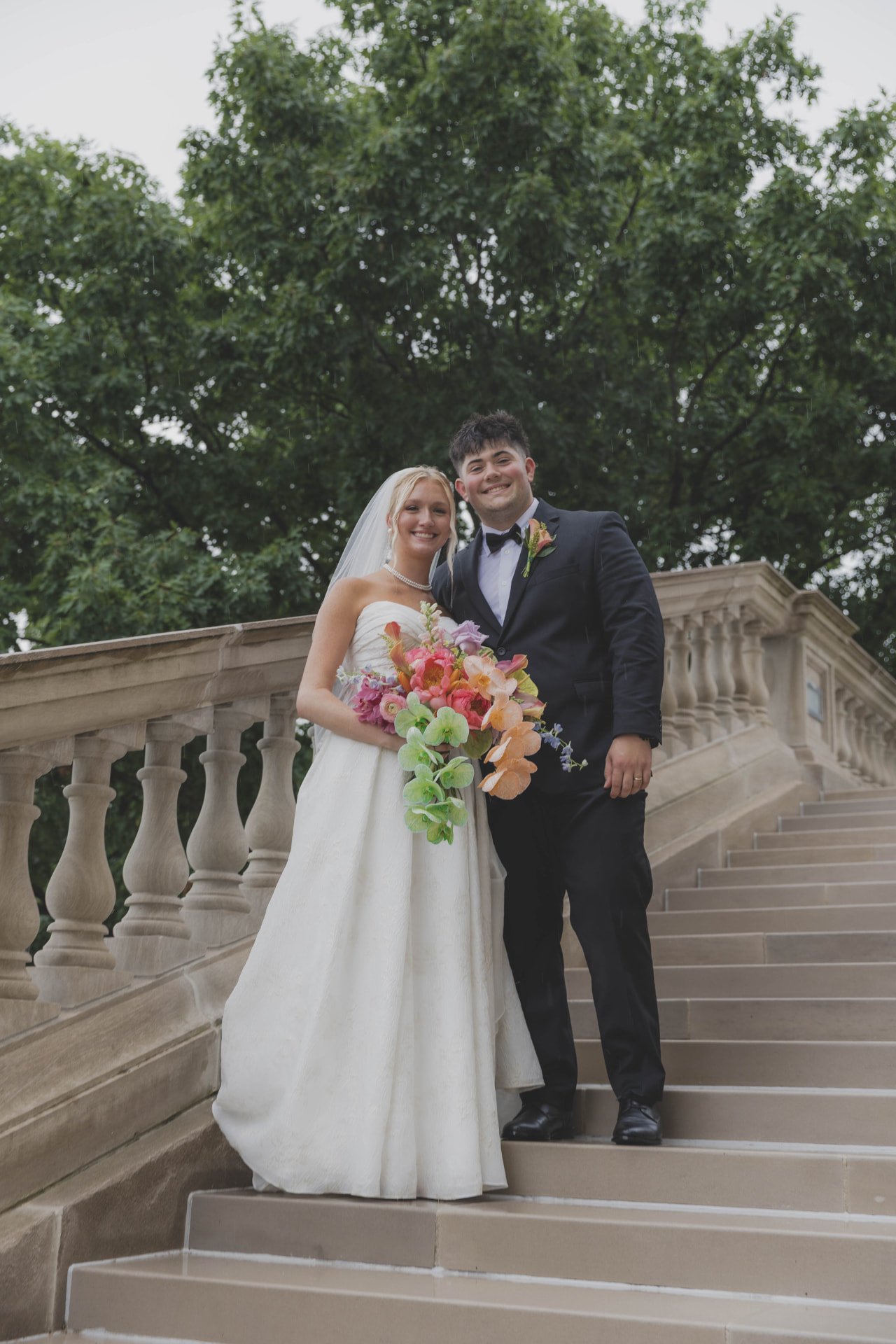 Bride and groom on stone steps with a bright bouquet at a Columbia, Missouri wedding